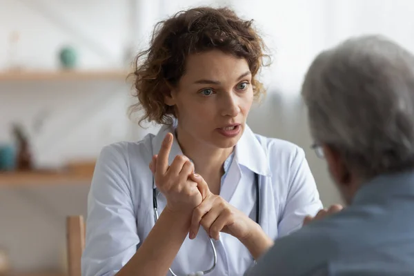 Vrouwelijke arts in gesprek met senior patiënt bij bezoek in het ziekenhuis — Stockfoto