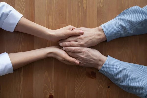 Woman doctor holding hands of senior man, loseup top view — Stock Photo, Image