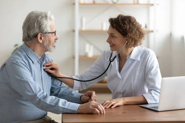 Vrouwelijke arts luisteren senior mannelijke patiënt hart met behulp van stethoscoop — Stockfoto