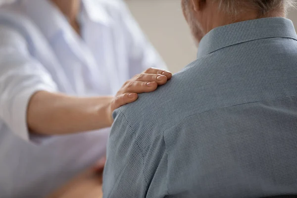 Close-up van vrouwelijke arts aanraken schouder van senior patiënt — Stockfoto