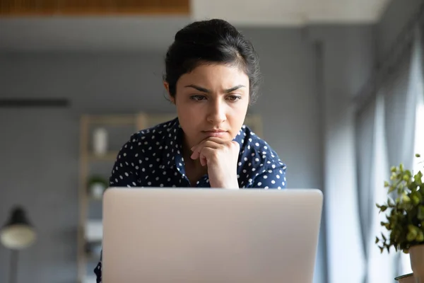 Testa colpo concentrato giovane donna indiana guardando monitor portatile . — Foto Stock