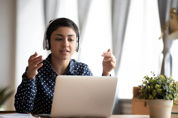 Gericht jonge indiase vrouw in koptelefoon op zoek naar computerscherm. — Stockfoto