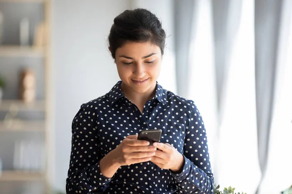 Agradável menina indiana milenar segurando smartphone, lendo boas notícias sms . — Fotografia de Stock
