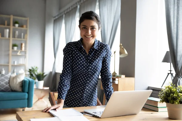 Sorridente giovane donna indiana freelance in piedi a tavola con il computer . — Foto Stock