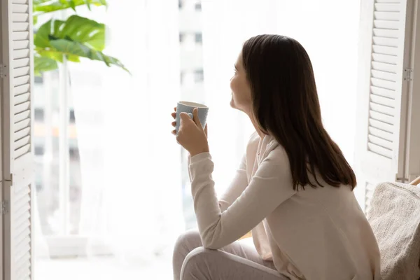 Dromerige vrouw ontspannen in fauteuil genieten van 's morgens koffie — Stockfoto