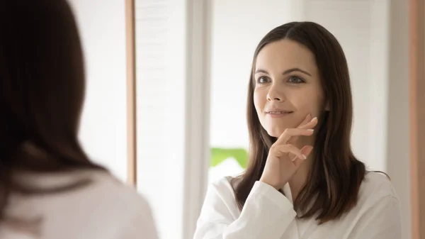 Jovem mulher olhar no espelho fazer procedimentos faciais — Fotografia de Stock