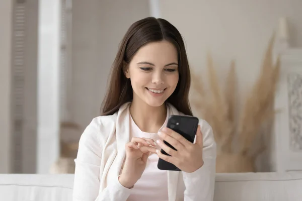 Chica sonriente usando mensajería en un smartphone moderno — Foto de Stock