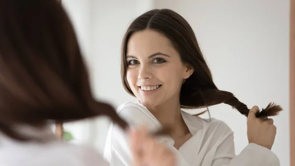 Mujer joven mirada en el espejo muestran grueso cabello sano —  Fotos de Stock