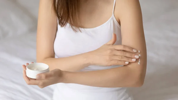 Young woman apply moisturizing body cream on arm — Stock Photo, Image