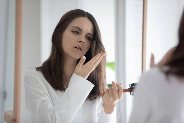 Ongelukkige jonge vrouw gefrustreerd door beschadigd haar — Stockfoto