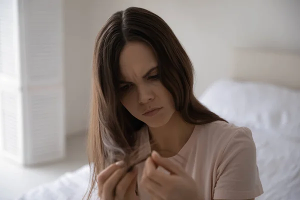 Ongelukkige jonge vrouw gefrustreerd door beschadigd haar — Stockfoto