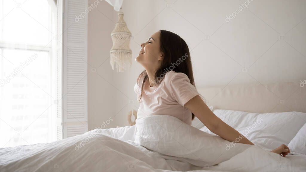 Happy young girl wake up in cozy white bed