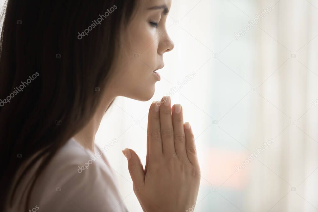 Superstitious young woman believer pray to God at home