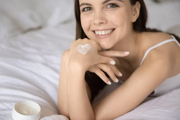 Retrato de sorrindo jovem mulher usando creme de mão — Fotografia de Stock