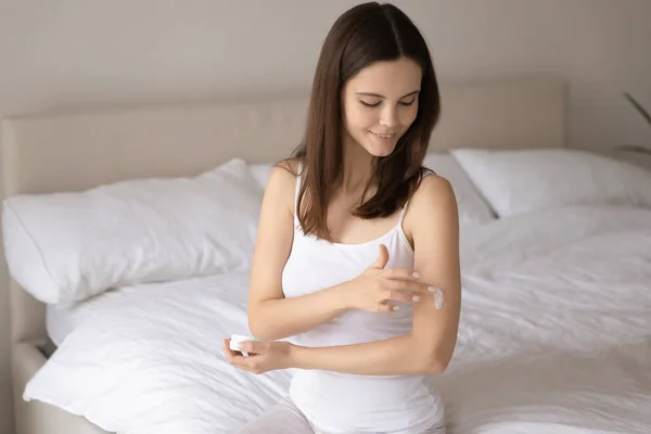 Jonge vrouw aan te brengen voedende lichaamscrème op arm — Stockfoto