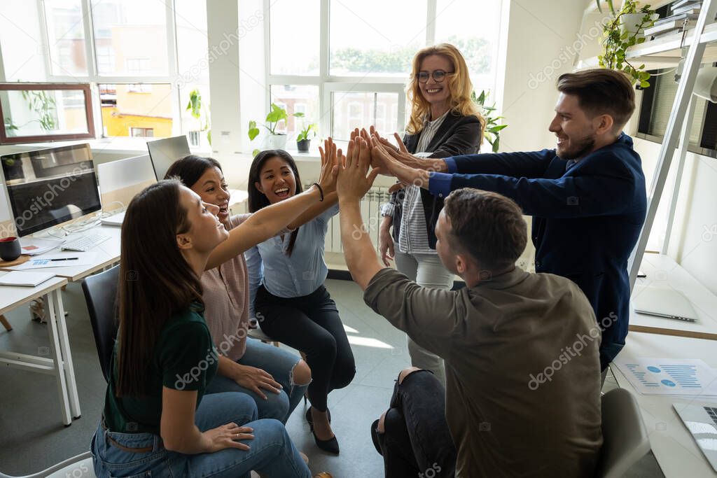Multiracial employees team with male leader, coach giving high five.
