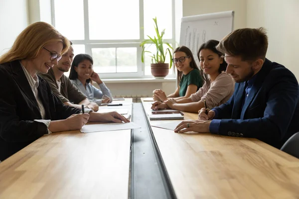 Sonriente mujer de negocios adulta que firma documentos con un hombre de negocios serio . — Foto de Stock