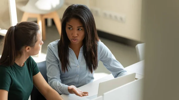 Serious joven afroamericana mujer de negocios hablando con el entrenador femenino . — Foto de Stock