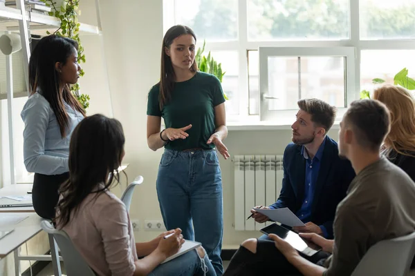 Serious female leader, mentor holding briefing for multiracial team interns. — Stock Photo, Image