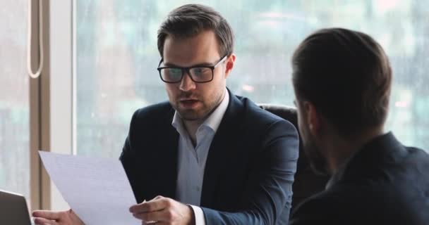 Självsäker affärsman i glasögon diskuterar kontraktsdetaljer med partner. — Stockvideo
