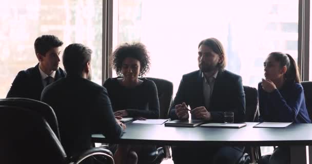 Recrutadores multirraciais confiantes em desgaste formal entrevistando jovem candidato masculino . — Vídeo de Stock