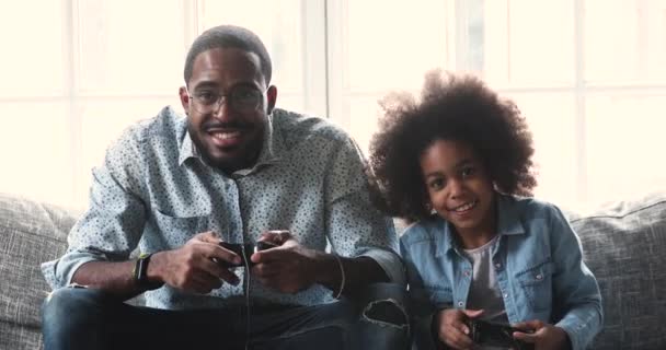 Überglückliches afrikanisches ethnisches kleines Mädchen spielt Videospiele mit Papa. — Stockvideo