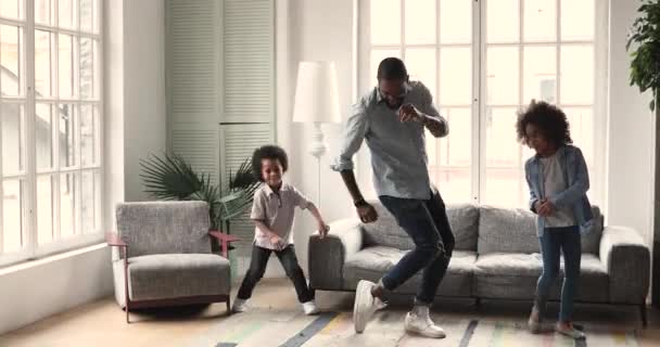 Smiling african ethnicity father showing dancing moves to children. — Stock Video