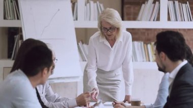 Ciddi yetişkin takım lideri iş arkadaşlarıyla iş meselelerini tartışıyor..