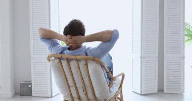 Rahat bir genç adam rahat bir sandalyede uzanıyor.