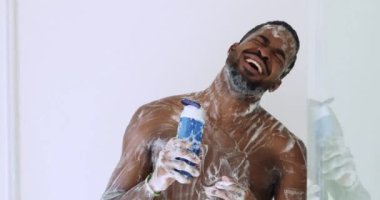 Duş alırken şarkı söyleyen neşeli, mutlu, Afro-Amerikan bir adam.