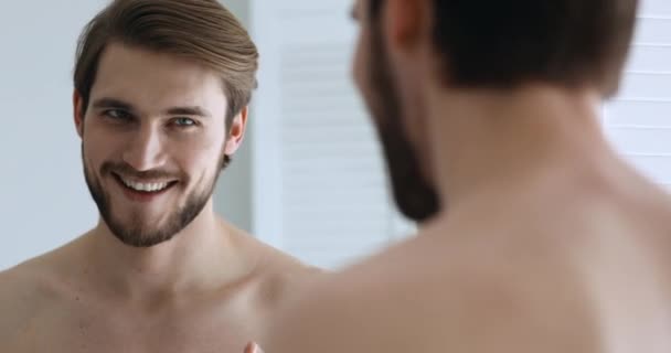 Zelfverzekerde jongeman spreekt tot zijn spiegelbeeld kijkend in spiegel — Stockvideo