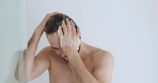 Young handsome man washing head with anti-dandruff shampoo taking shower — Stock Video