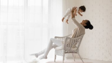 Gülümseyen Afrikalı Amerikalı anne bebek bebekle oynuyor.