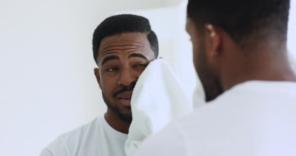 Happy african man wiping face with towel looking in mirror — Stock Video