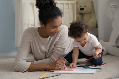 Küçük bebekle çizim yapan melez bir anne.