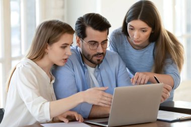 Çeşitli meslektaşlar dizüstü bilgisayarda birlikte çalışıyor.