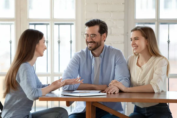 Felice giovane coppia parlare con agente immobiliare a incontro — Foto Stock