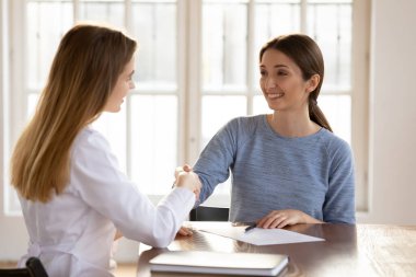 Gülümseyen doktor ve kadın hasta toplantıda el sıkışıyor.