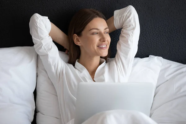 Donna sorridente seduta a letto con notebook al mattino — Foto Stock