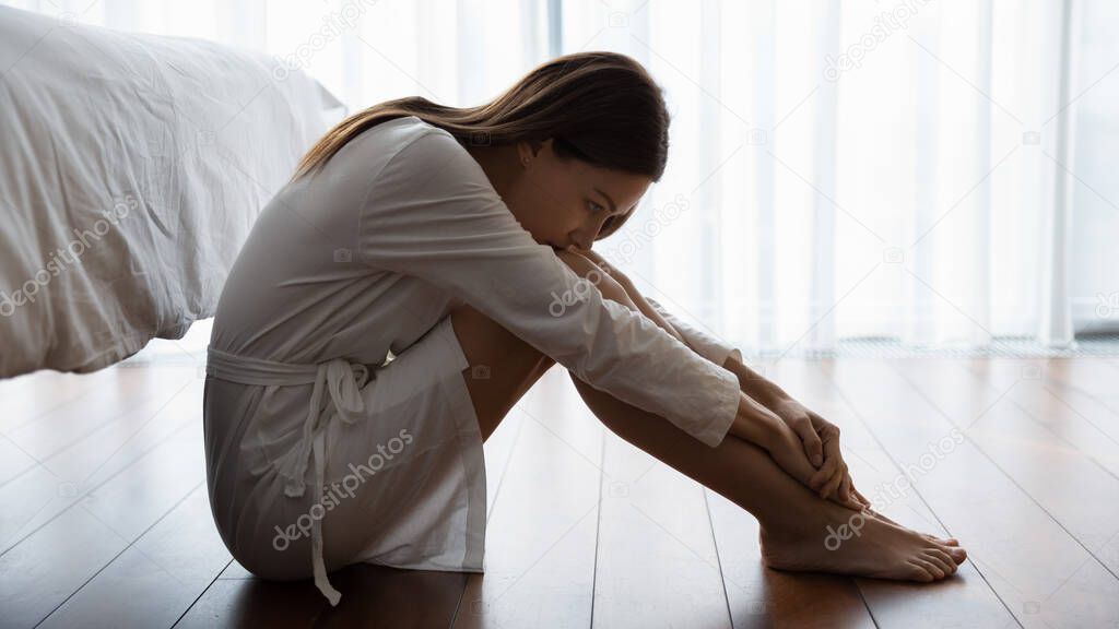 Sad woman sitting on floor looking unhappy suffers from loneliness