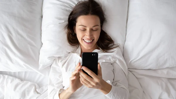 Top view mujer acostada en la cama utilizar mensajes de verificación del teléfono celular — Foto de Stock