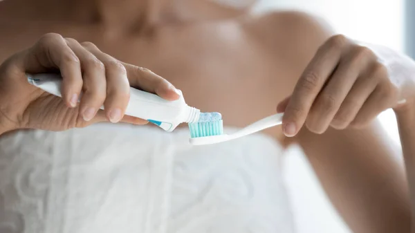 Closeup image toothpaste from tube being applied to toothbrush — Stock Photo, Image