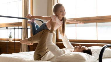 Mutlu baba yatak odasında küçük kızıyla oynuyor.