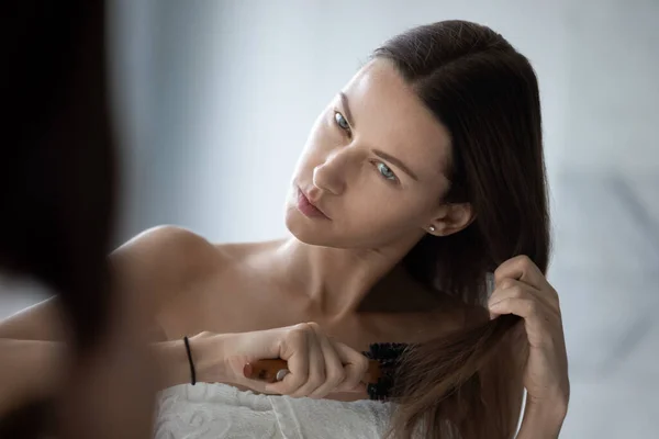 Woman combing hair looking dissatisfied by naughty tangled hair — Stock Photo, Image