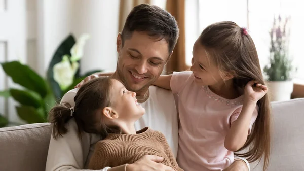 Щасливий люблячий молодий батько обіймає двох маленьких дочок — стокове фото
