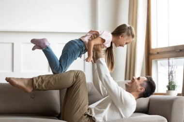 Gülümseyen baba küçük kızıyla oturma odasında oynuyor.