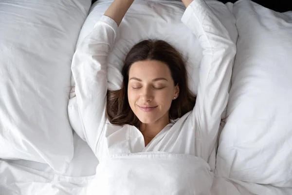 Woman stretching hands waking up after night sleep top view