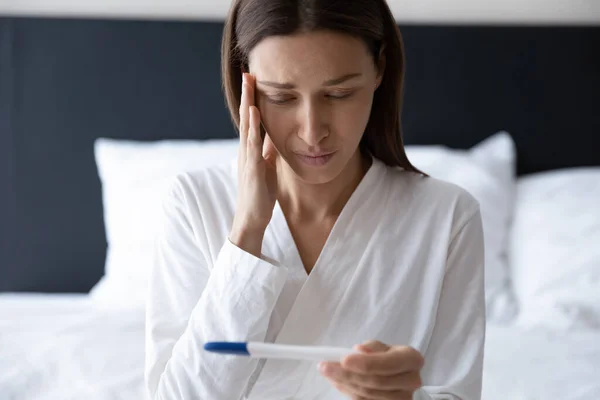 La donna che guarda il test di gravidanza si sente in ansia per le cattive notizie — Foto Stock