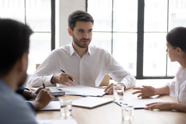 Ciddi bir iş adamı genç bayan çalışanla proje hakkında konuşuyor.