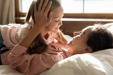Mutlu anne ve tatlı küçük kız yatakta yatıyor.